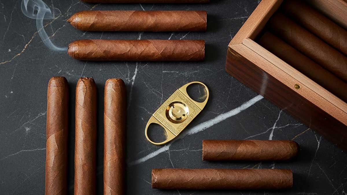 uxury flat lay of rare expensive cigars on dark marble with humidor and gold cutter.